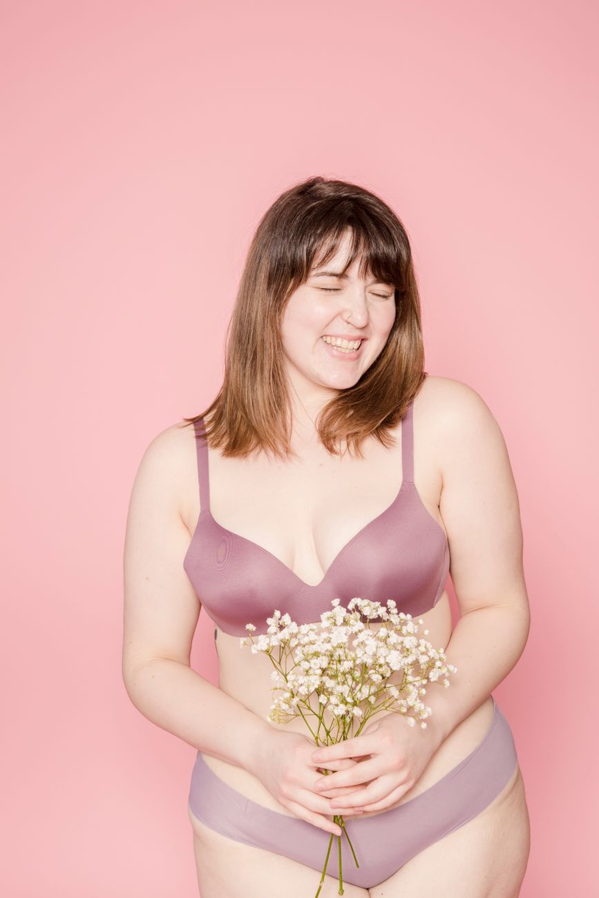 joyful overweight asian woman in lingerie with bouquet in hands