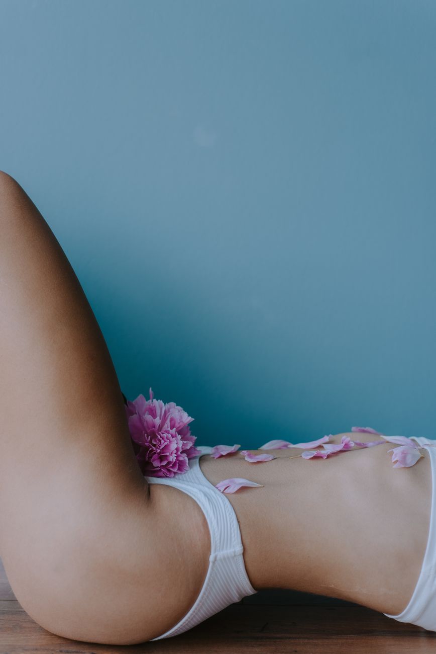 person in white bikini with pink petals on her tummy