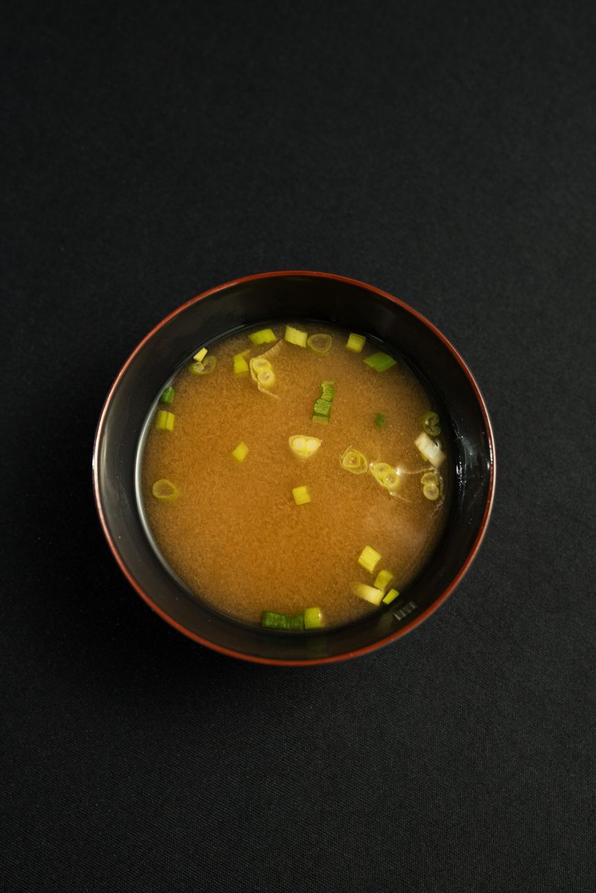 delicious miso soup with green onions in black bowl